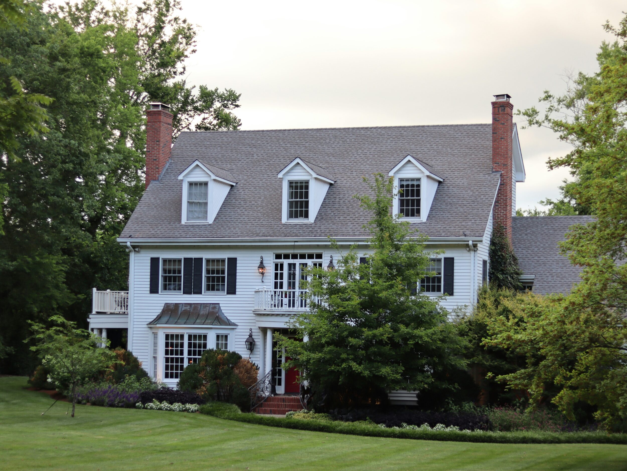 Exterior shot of a colonial-style home featuring tall windows and symmetrical features. Image credit Elijah Crouch on Unsplash.