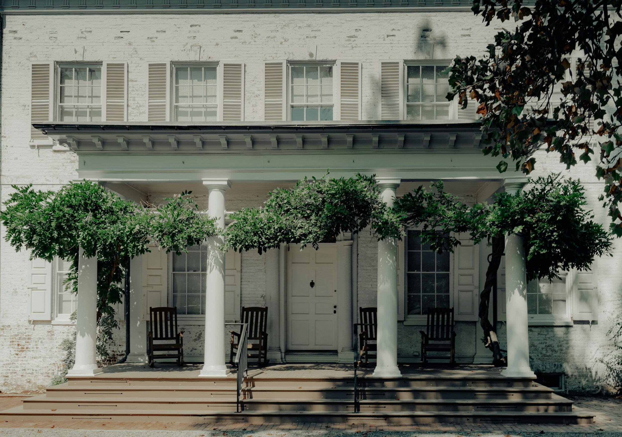 Exterior shot of a Greek revival home with white painted brick. Image credit Y M (ymoran) on Unsplash.