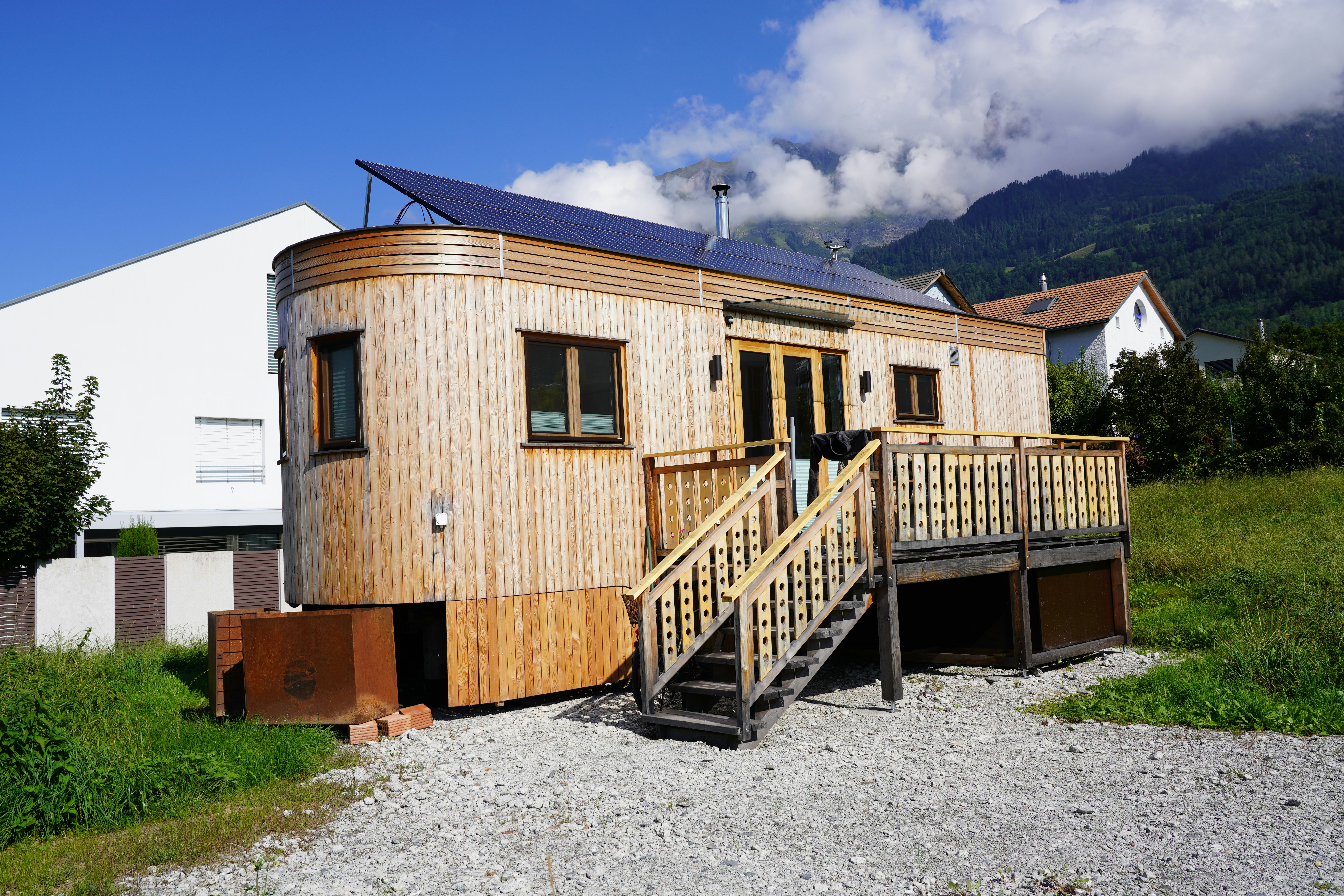 Exterior shot of a mobile home with a porch, wood siding, and solar panels on the roof. Image credit Harry Pepelnar on Unsplash.